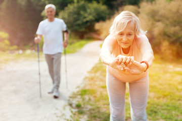 Naklejka na ściany i meble Active elderly woman doing a bending exercise