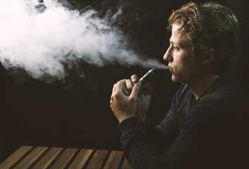 Isolated young man holding and vaping an electronic cigarette or e cig.