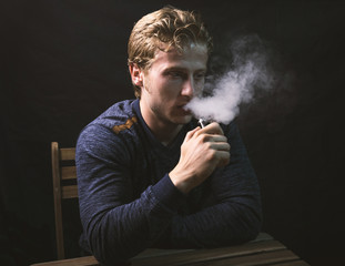 Isolated young man holding and vaping an electronic cigarette or e cig.