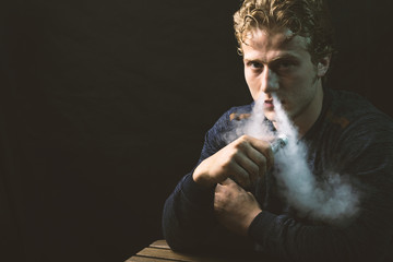 Isolated young man holding and vaping an electronic cigarette or e cig.