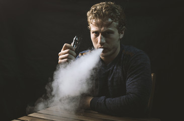 Isolated young man holding and vaping an electronic cigarette or e cig.