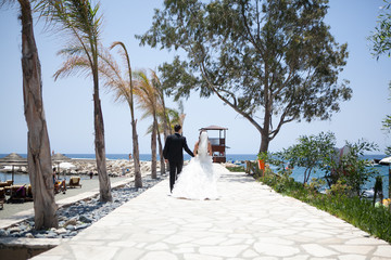 Couple smiling and embracing near wedding arch on beach. Honeymoon on sea or ocean