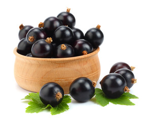black currant in wooden bowl with green leaf isolated on white background