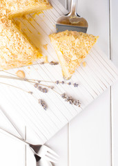 Napoleon cake with lavender custard on a white wooden background, selective focus, vertical