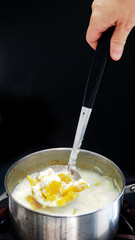 Handles scoop boiled pumpkin with coconut milk in pot