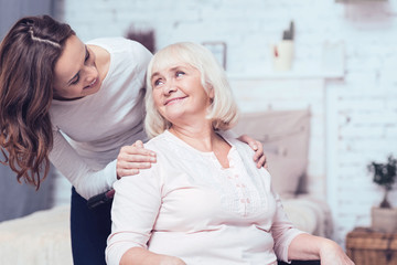 Cheerful woman taking care of her grandmother on wheelchair