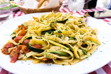 Pasta with pesto sauce and tomato on a the table