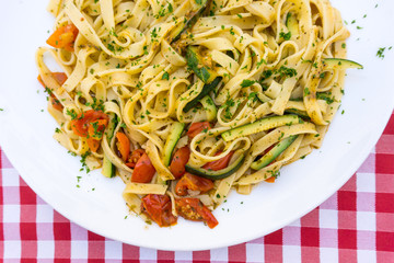 Pasta with pesto sauce and tomato on a the table
