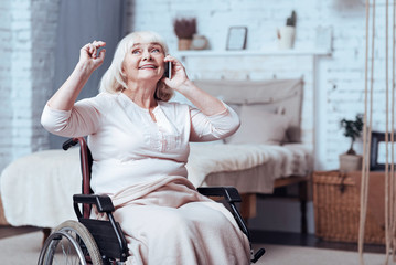 Joyful handicap aged woman talking on smart phone at home