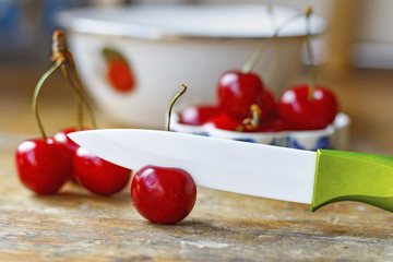 Sweet red cherry with ceramic knife on an old wooden table