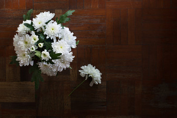 White flowers in the vase put on the old wooden floor in dim light room / Still life and select focus and space for text..