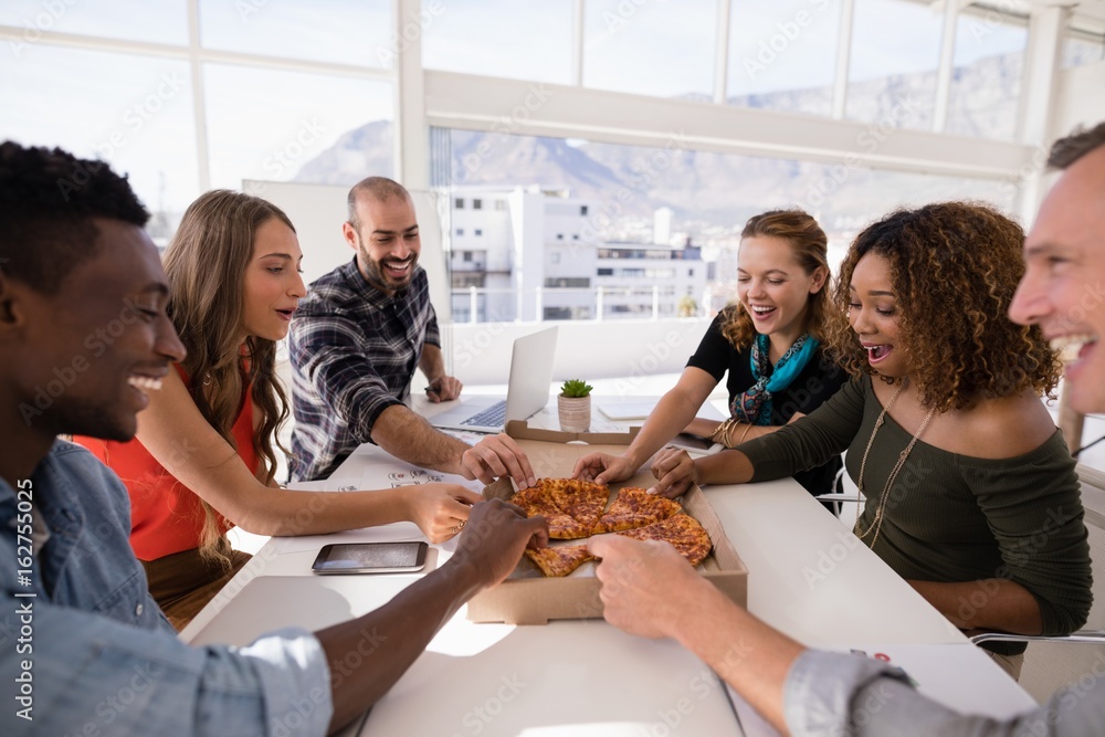 Wall mural happy executives sharing pizza in conference room