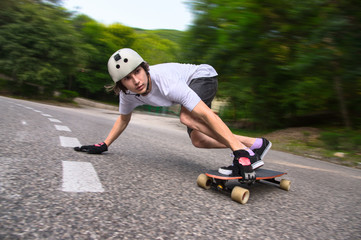 Young man is going to slide, slide with sparks on a longboard on the asphalt