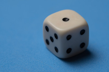 Closeup of single white cubic dice isolated over blue background