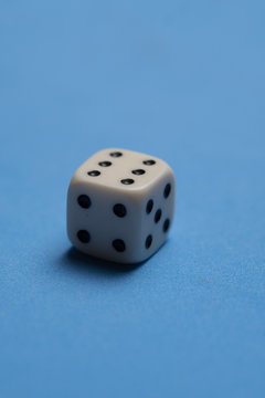 Closeup of single white cubic dice isolated over blue background