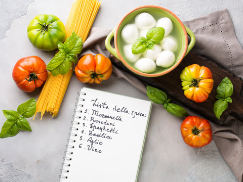 Pasta, tomato, mozzarella still life on gray rustic background. Traditional products and food shopping list for spaghetti with tomatoes in Italian