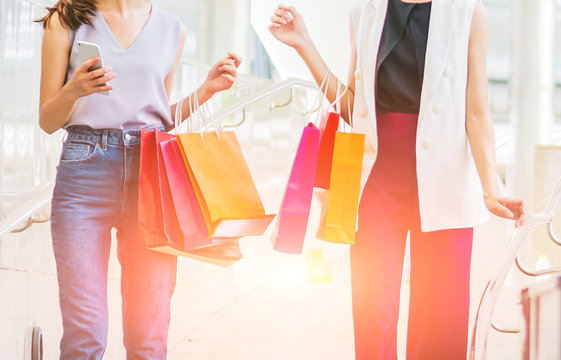 two young women hand holding smart phone and shopping bag, sale, consumerism and people concept.