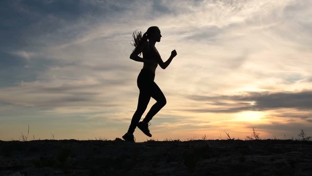 Young lady running on seashore at sunset