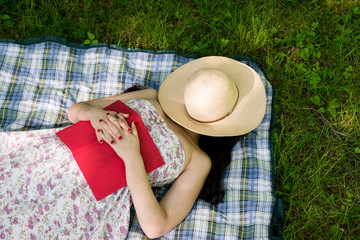 Woman sleeping in the grass outside while reading a book