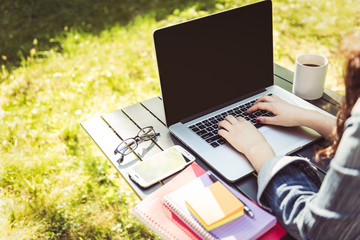 Freelance Work. Casual dressed woman sitting at desk outside in a garden working on a laptop