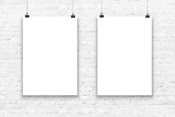 Two blank paper poster mockup on a white brick wall.
