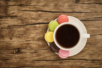 Colorful macaron and cup of coffee with wooden table