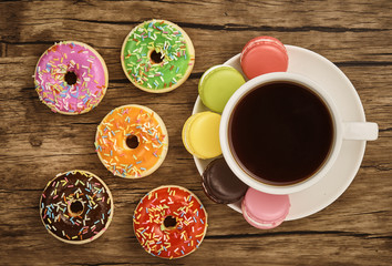 Fototapeta na wymiar Doughnut, colorful macaron and cup of coffee with wooden table