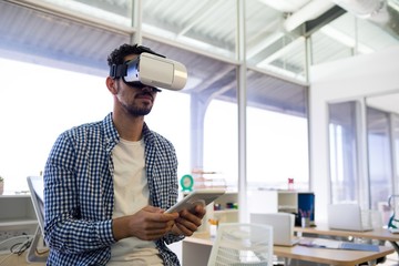 Male executive using virtual reality headset and digital tablet