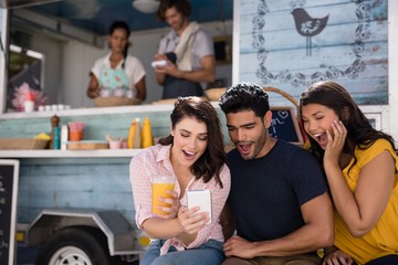 Friends using mobile phone at food truck van