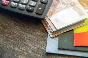 Thai banknotes and calculator on wood background