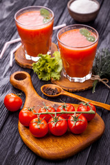 Glass of fresh tomato juice and tomatoes on a wooden cutting board