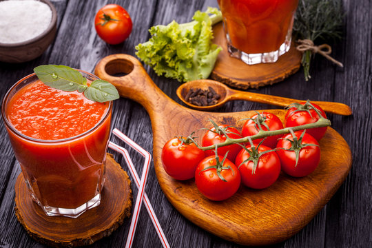 Glass of fresh tomato juice and tomatoes on a wooden cutting board