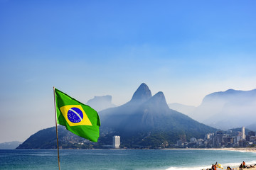 Brazilian flag at Ipanema beach in Rio de Janeiro with Two Brothers hill and Gavea stone in background