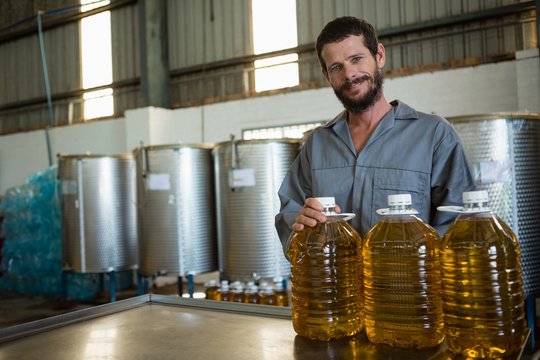 Worker standing with can of olive oil in factory