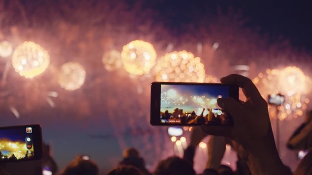 Hands of peoples taking photo to fireworks on smartphone. Close-up. Slow motion