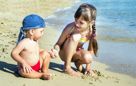 The older sister and younger brother on the seashore look at each other