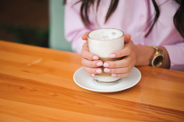 Woman drinking hot cappuccino coffee and eating cake at cafe.