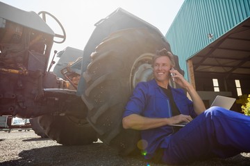 Worker talking on mobile phone while using laptop on a sunny day © WavebreakMediaMicro
