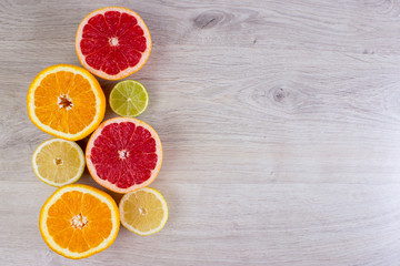 Citrus fruits cut background- oranges, lemons, limes, grapefruit on a bright wooden background