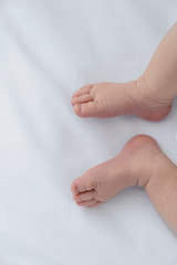 Close up of tiny adorable bare pink baby feet as the infant sleeps on white blanket