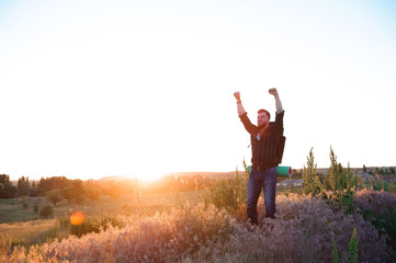 Young man is looking at sunset. Traveller with backpack.