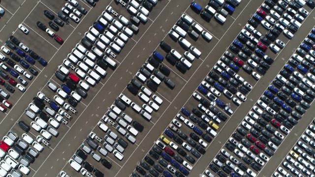 Aerial top down view above car lot with ready for transportation towards car dealers automobiles are white blue black and red colored and parked very close to each other industrial scenery 4k quality