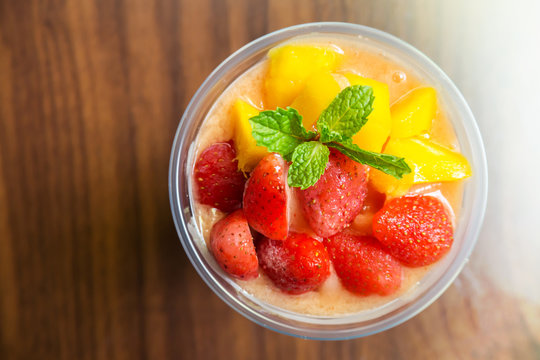 Mango and strawberry smoothies in plastic cup. Refreshment healthy drink.
