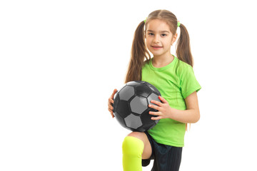 little cute girl with giant holds the ball and looks into a camera