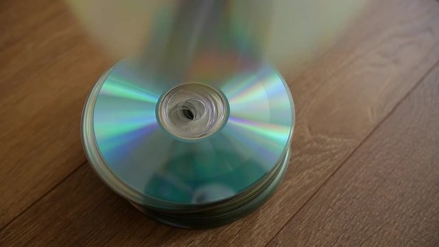 Closeup of a stack compact discs on wooden floor background. Cd falling from the top, slow-motion.