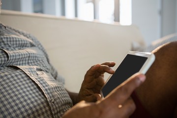Senior man using digital tablet in the living room at home