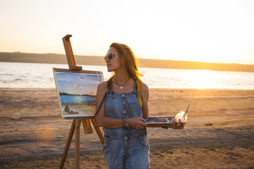 Obraz premium Young woman artist painting landscape in the open air on the beach