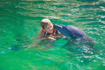 A boy, a baby, a model bathes with dolphins. Man, a mammal, a dolphin.