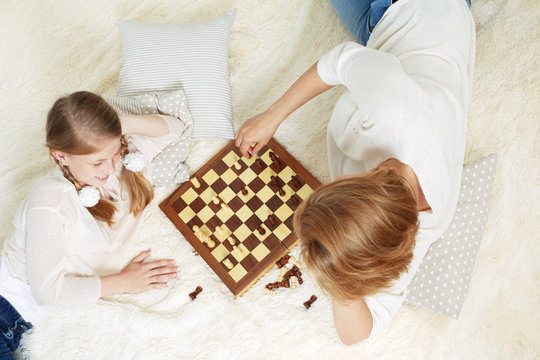 Mother and child are playing chess while spending time together at home