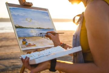 Young woman artist painting landscape in the open air on the beach, close up - 162772275